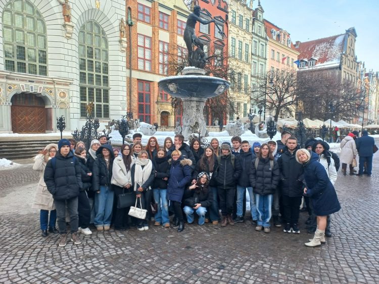 grupa ludzi stojąca koło fontanny Neptuna w Gdańsku