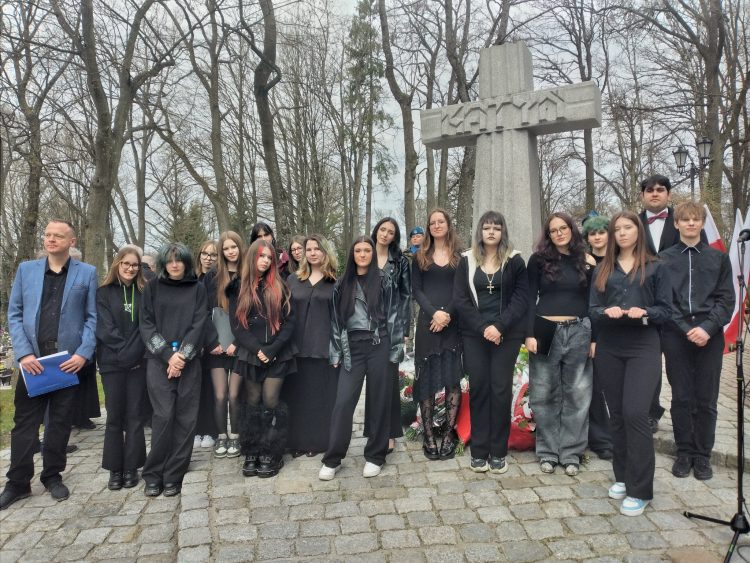 młodzież stojąca przed krzyżem katyńskim na cmenatrzu