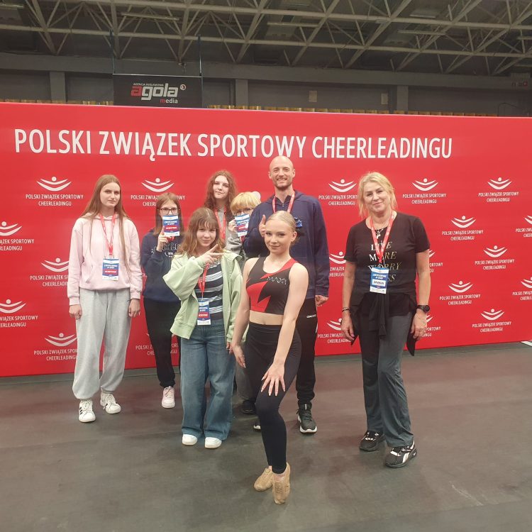 młodzież z nauczycielami pozuje do zdjęcia na ściance z napisem Polski Związek Cheerleadingu